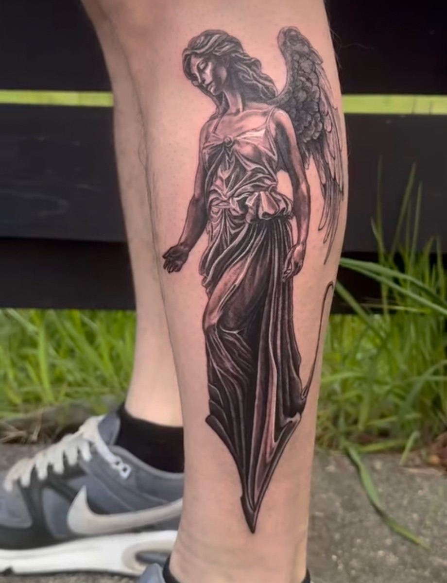 Detailed black-and-grey angel statue tattoo on the calf, done at Long Island Ink in Atlanta